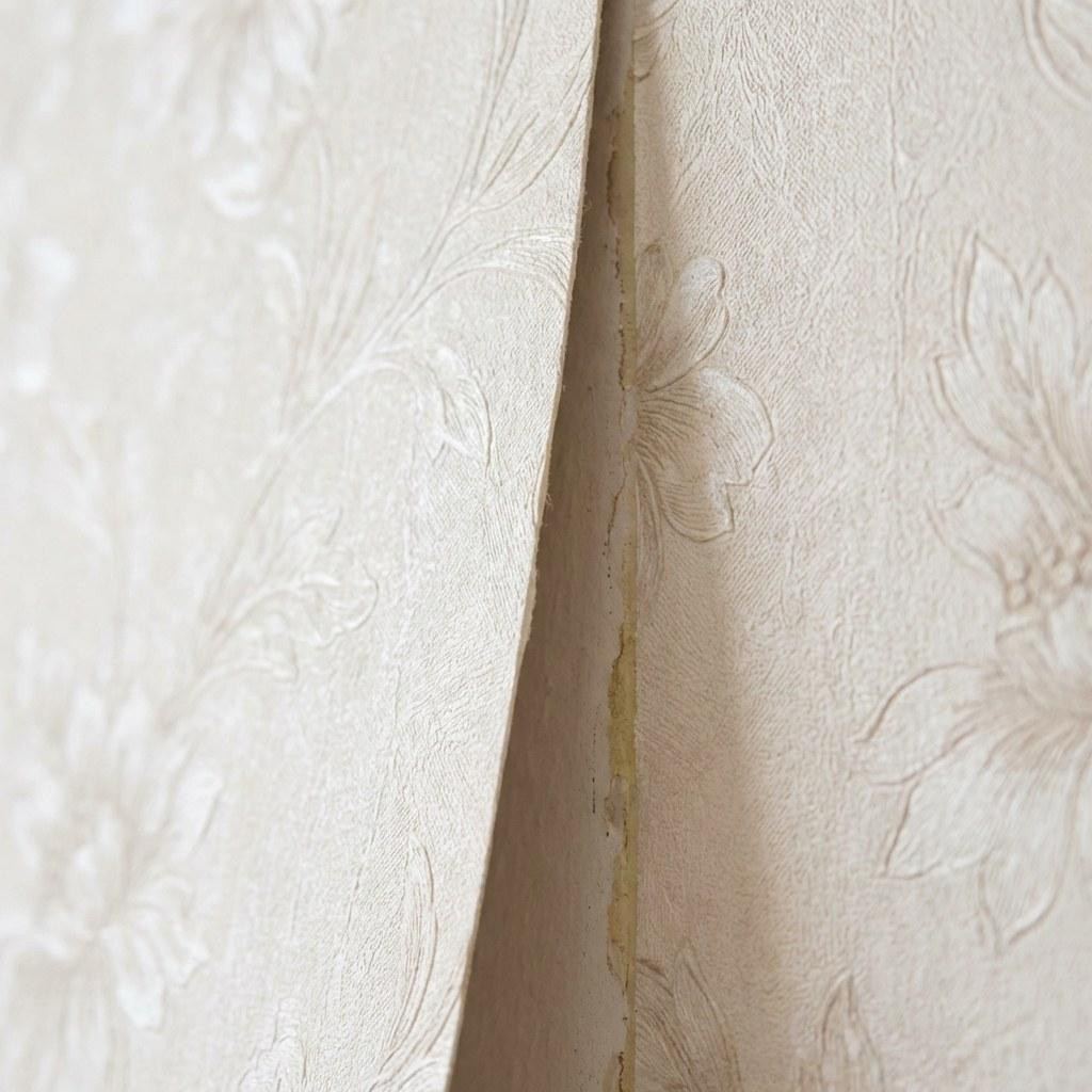 Close-up of a wallpaper seam peeling slightly away from the wall