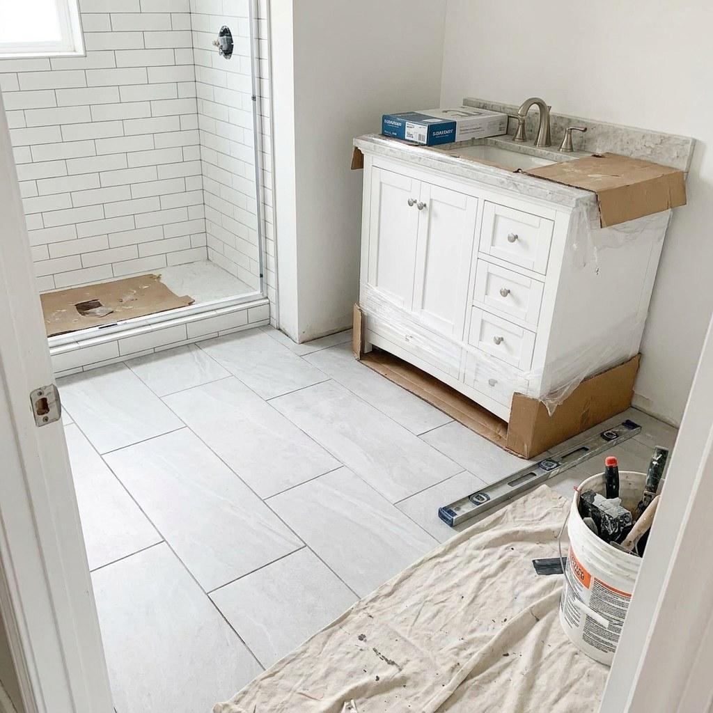 A bathroom mid-renovation showing exposed subfloor and newly laid tile