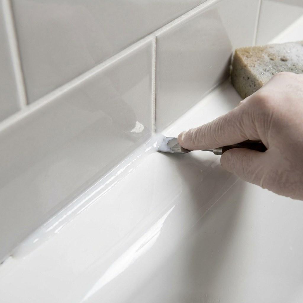 A clean bead of silicone caulk sealing the joint between a bathtub and tile wall